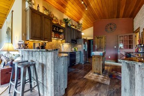 Cozy kitchen with a central island and casual dining area, featuring a large clock and ample kitchen appliances.