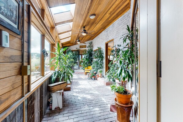 Corridors lined with potted plants and framed pictures, featuring benches and a small cart.