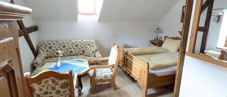 A cozy room with a wooden bed, a sofa, and a small table with chairs.