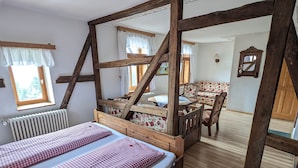 Una habitación con una cama con dosel, una mesa de madera con sillas y vistas a un bosque por una ventana.