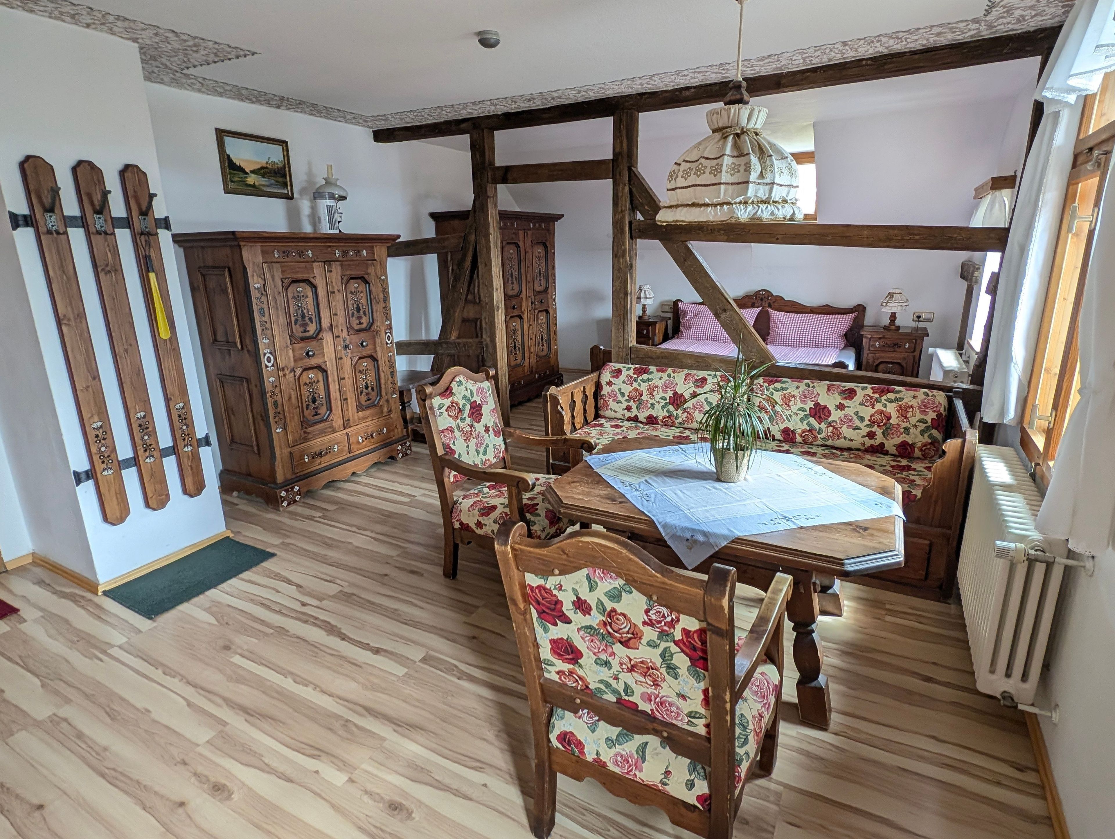 Une pièce à l’ambiance traditionnelle, avec des meubles en bois, une table à manger et un banc doté d’un revêtement à motifs floraux.