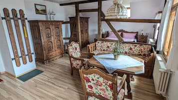 Une pièce à l’ambiance traditionnelle, avec des meubles en bois, une table à manger et un banc doté d’un revêtement à motifs floraux.