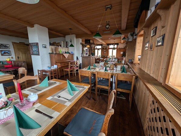 A restaurant with wooden interiors, tables set with green napkins, and a variety of dishes.