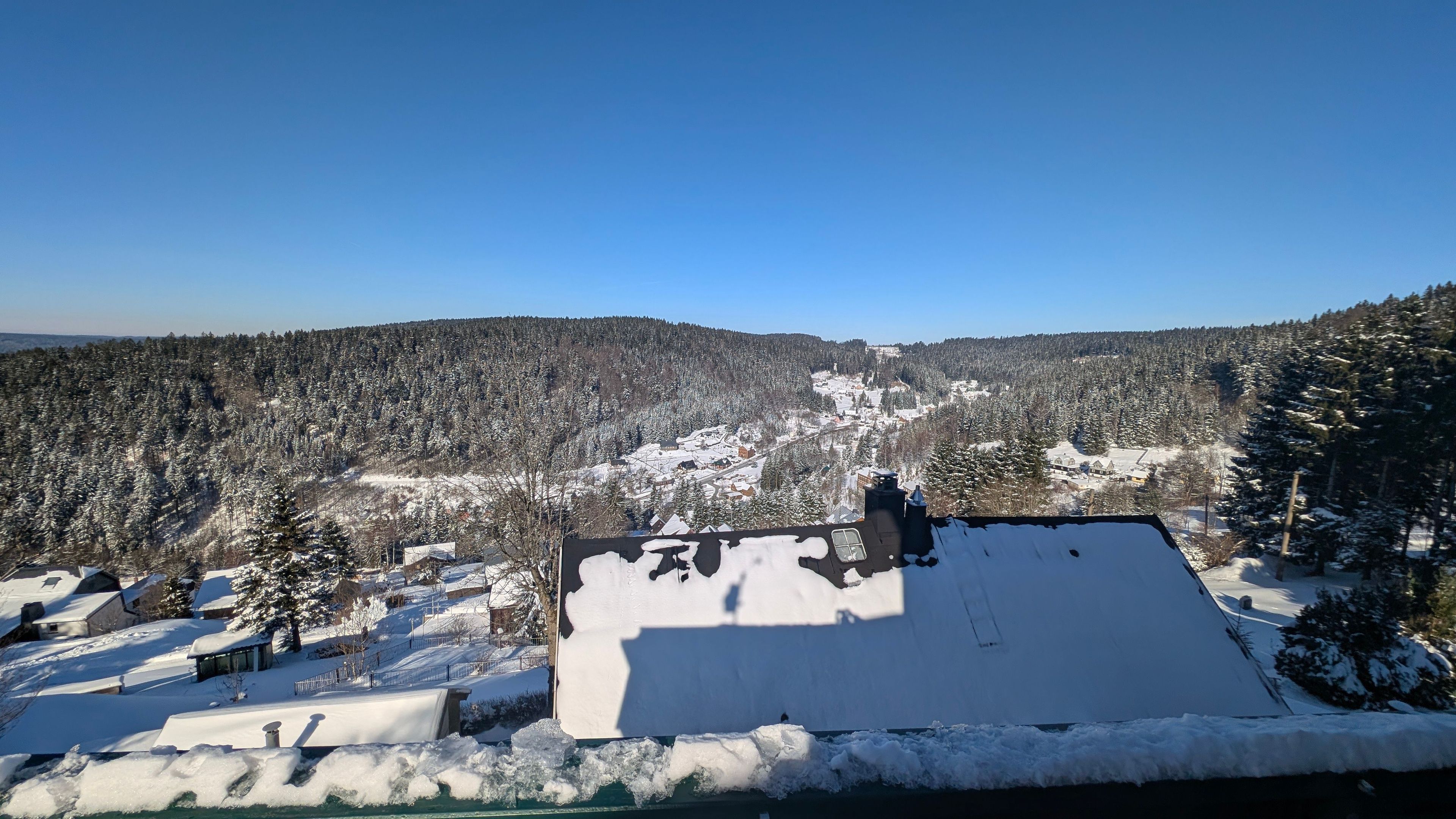 Un paysage enneigé avec un bâtiment doté d’un toit plat et d’une cheminée.