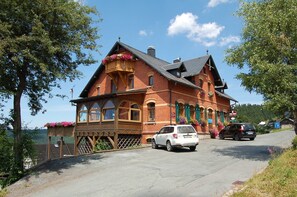 A traditional brick building with a balcony, a car parked in front, and a sign indicating a restaurant.