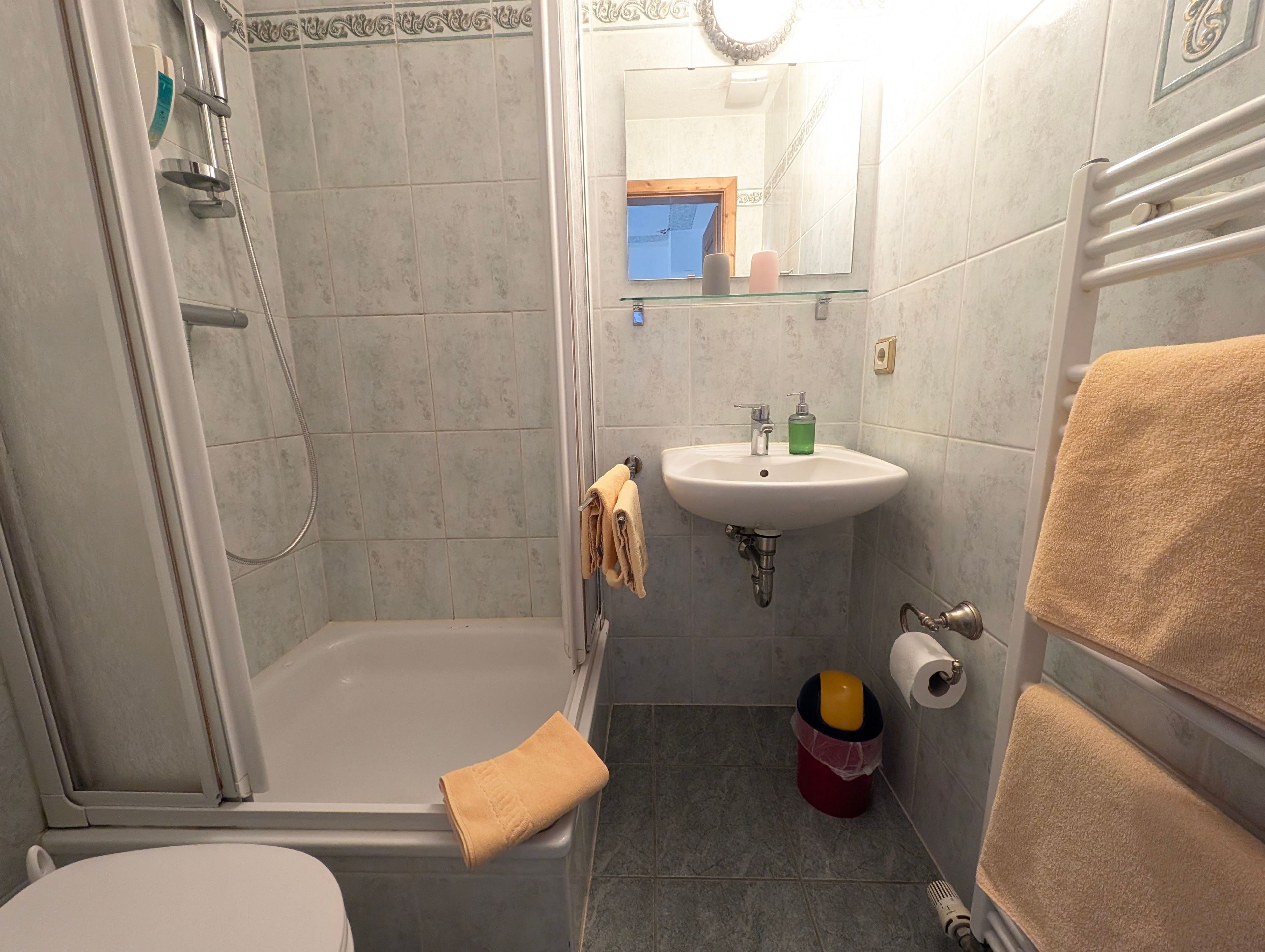 Ein Badezimmer mit Dusche, Toilette, Waschbecken und Spiegel.