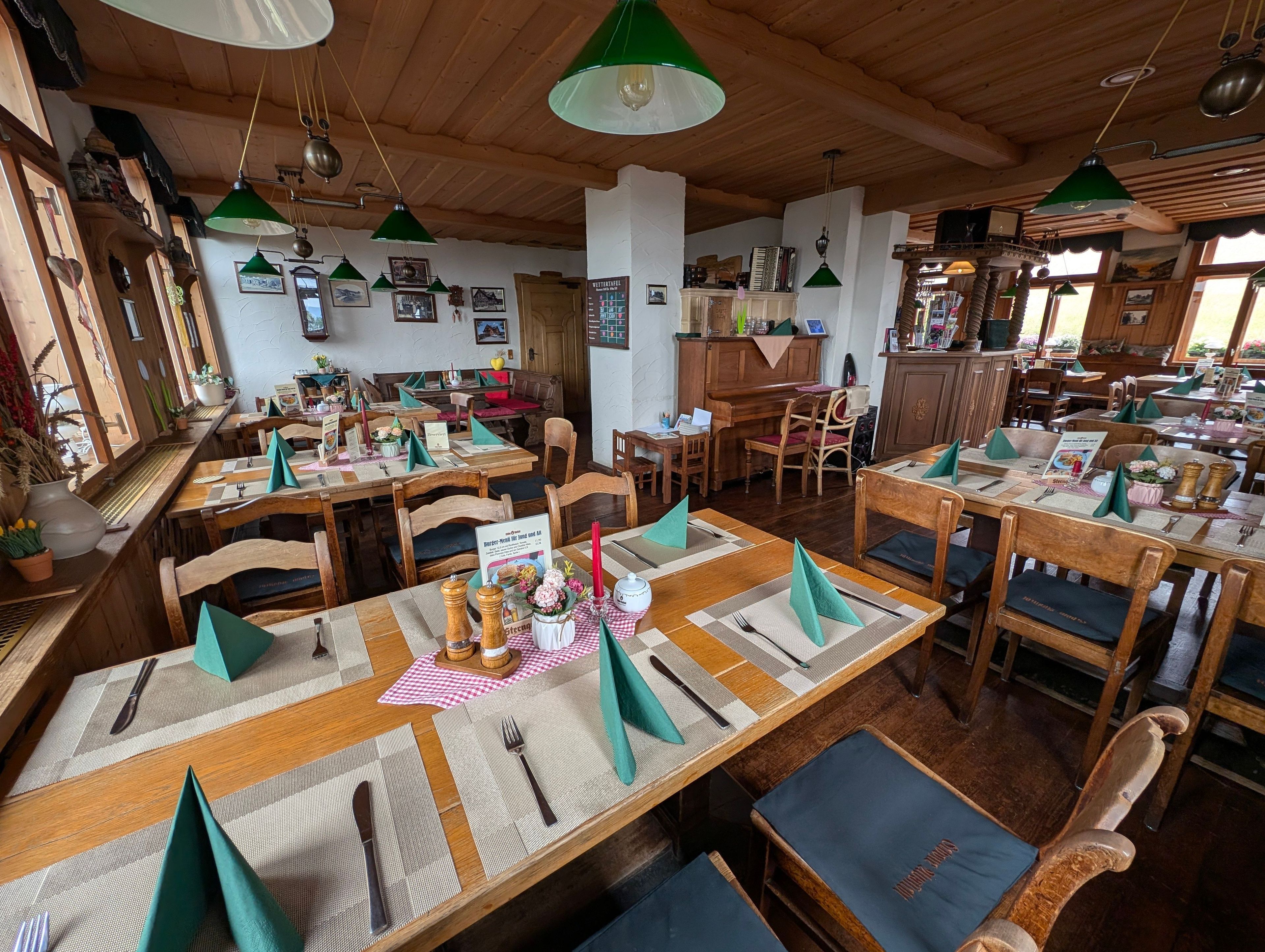 A restaurant with wooden tables, green napkins, and various dishes.