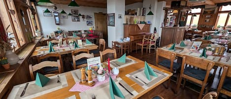 A restaurant with wooden tables, green napkins, and various dishes.