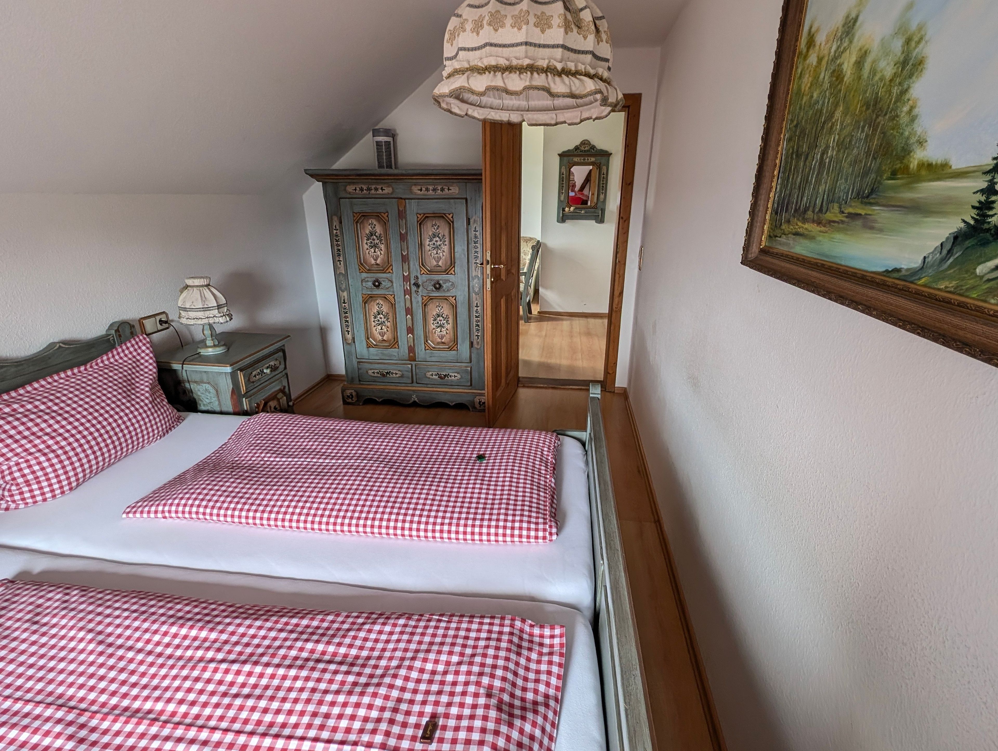 A bedroom with a bed, a dresser, a mirror, and a painting.