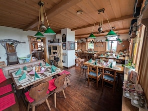 Un restaurant au décor intérieur en bois, avec des lampes suspendues vertes et des tables et chaises en bois.