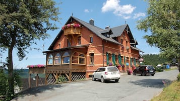Un bâtiment traditionnel en briques, doté d’un balcon, avec une voiture garée devant et une enseigne indiquant qu’il s’agit d’un restaurant.