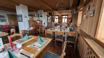 Un restaurant au décor intérieur en bois, avec des tables nappées de serviettes vertes et une grande variété de plats au menu.