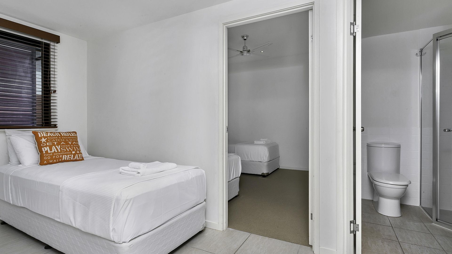 Une chambre à coucher avec un lit, un oreiller orné d’un motif, une salle de bain avec des toilettes et une douche.