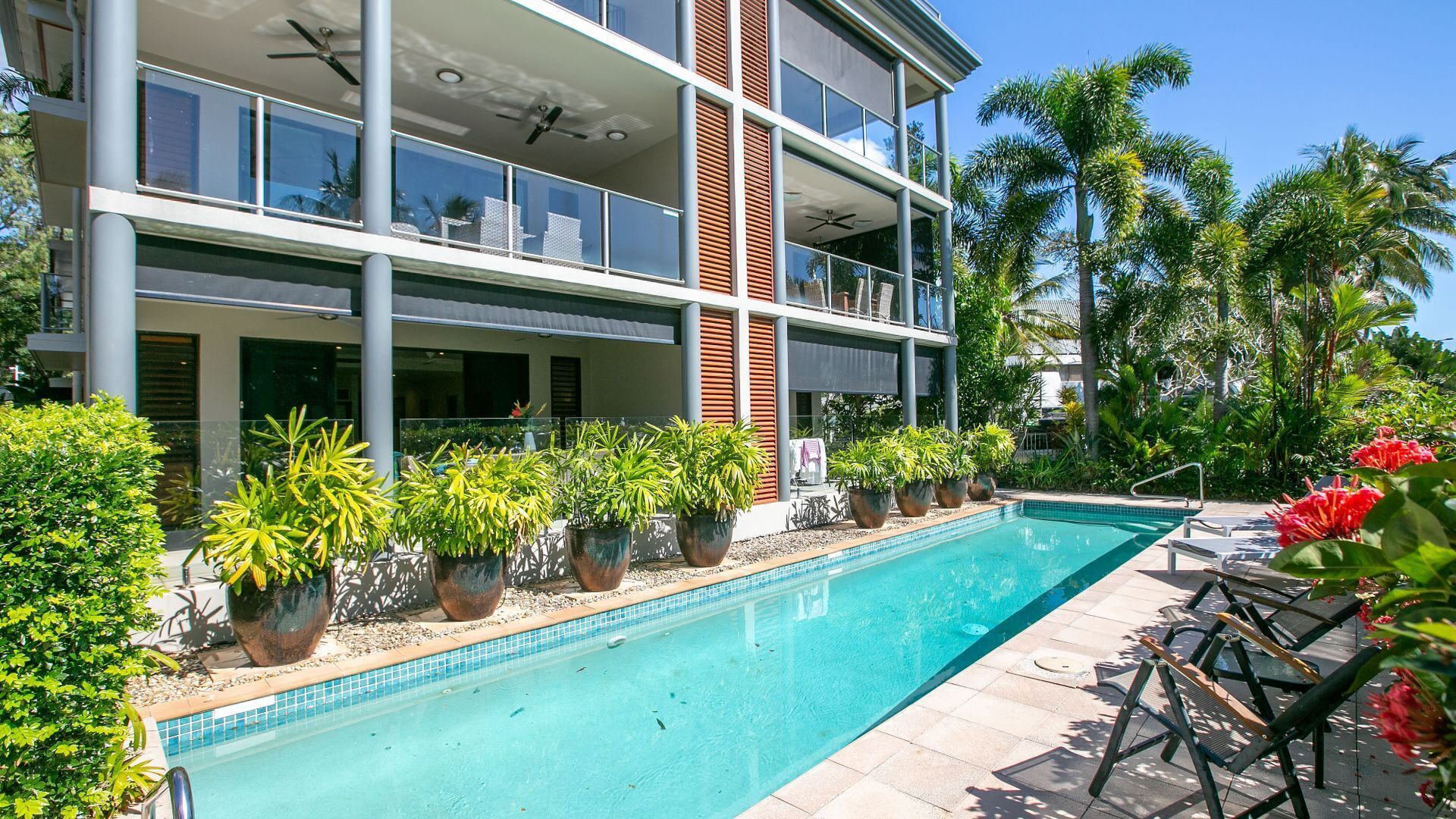 A modern hotel with a pool, outdoor seating, and lush greenery.