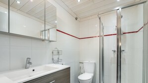 Une salle de bain moderne avec un grand miroir, un meuble-lavabo à deux vasques, des toilettes et une douche à parois de verre.