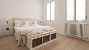A bedroom with a bed, bedside tables, a radiator, and a window.