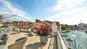 A rooftop terrace with outdoor seating, a view of the city, and a river.