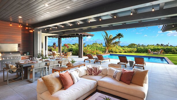 A modern outdoor living area with a pool, a dining setup, and a large sofa.