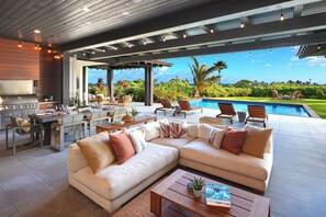 Un'area esterna moderna con piscina, angolo pranzo e un ampio divano.