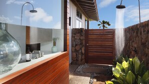 A modern bathroom with a large mirror, a wooden vanity, and a stone wall.