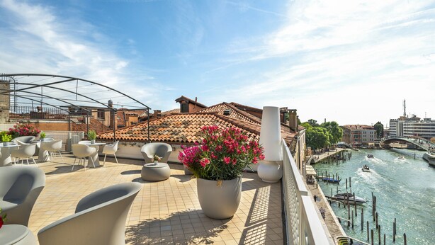 Une terrasse sur le toit avec des sièges extérieurs, une vue sur la ville et une rivière.