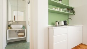 A modern kitchen with white cabinets, a white sink, and a green accent wall.