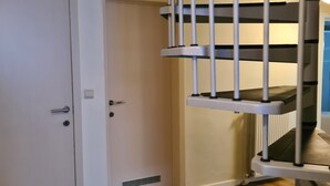 A room with a spiral staircase, a white door, and wooden flooring. - Beautiful very quiet Gite (Büllingen)