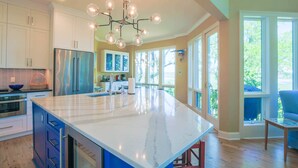 A spacious kitchen with a large island, stainless steel appliances, and a unique chandelier.
