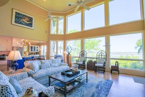A spacious living room with large windows, a ceiling fan, and a dining area with a view.