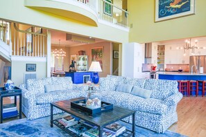 A spacious living room with a patterned sofa, a coffee table, and a staircase leading to an upper level.