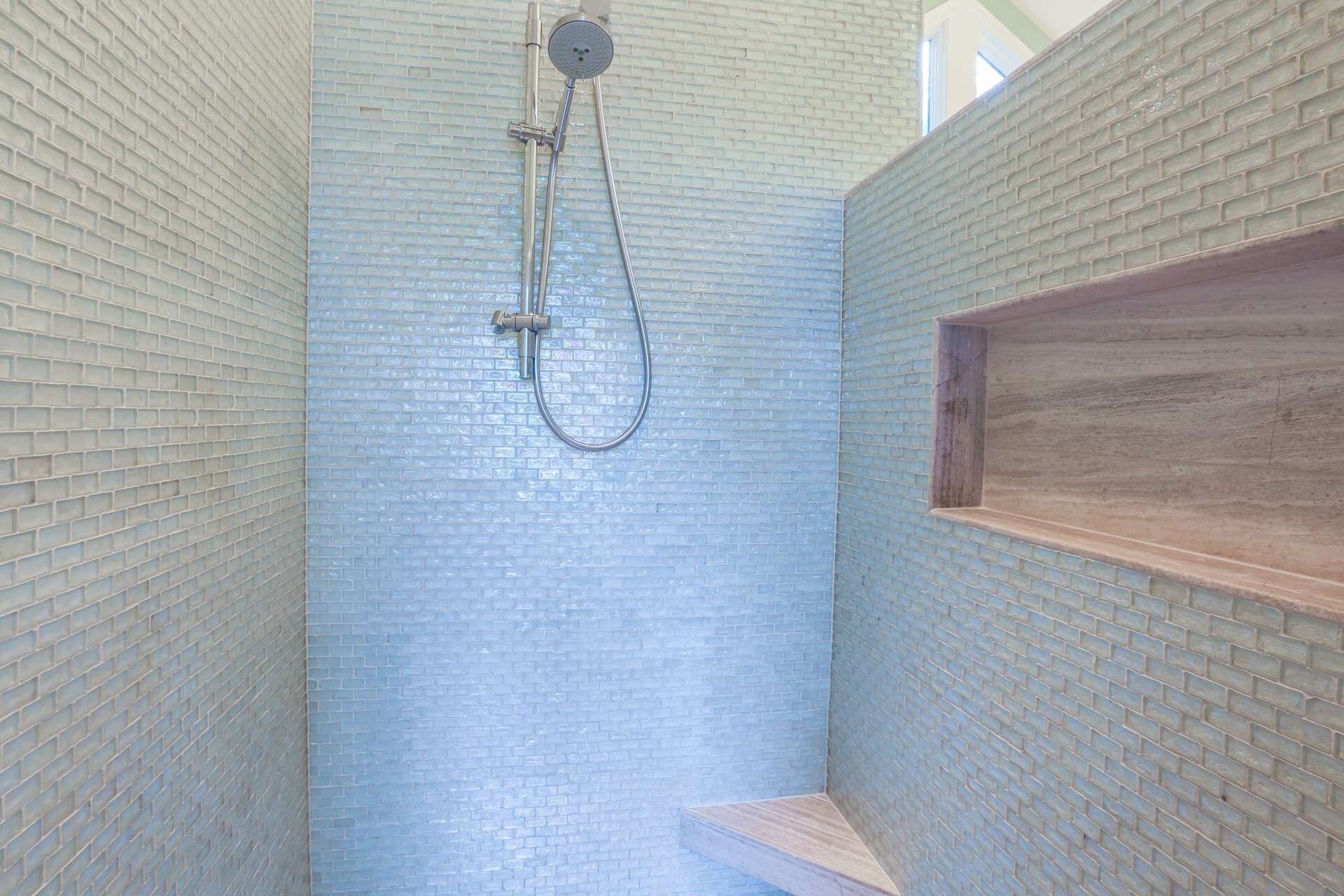 A shower with a glass block wall and a wooden shelf.