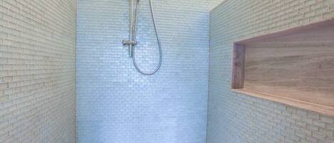 A shower with a glass block wall and a wooden shelf.