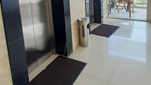 Un espace moderne avec deux ascenseurs, une poubelle et une vue sur un espace extérieur aménagé avec des sièges.