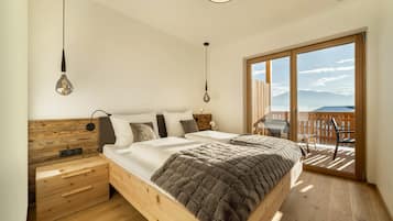 Une chambre avec un lit en bois, une table de chevet, une commode et un balcon avec vue.