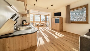 A modern kitchen with a wooden countertop, a sink, and a dining area with a table and chairs. - Friendly Apartment "Zirbe in the Nockerhof" with Mountain View, Wi-Fi & Terrace (Andrian)