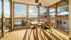 A room with large windows, a wooden table, chairs, and a hanging light fixture. - Welcoming Apartment "Eiche im Nockerhof" with Mountain View, Wi-Fi & Terrace (Andrian)