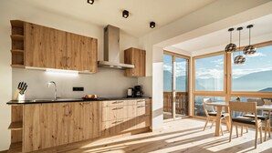 A modern kitchen with wooden cabinets, a stainless steel range hood, and a large window overlooking a mountainous landscape. - Welcoming Apartment "Eiche im Nockerhof" with Mountain View, Wi-Fi & Terrace (Andrian)