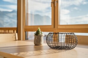 Una mesa de madera con una cesta de alambre y una pequeña planta en maceta.