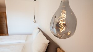 Una camera da letto con un letto, cuscini, una lampada a sospensione e una testiera in legno.