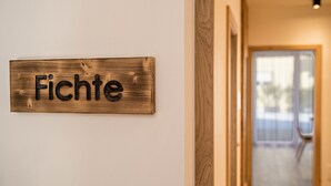 Un segnale di legno con la scritta 'Fichte' su un muro bianco.
