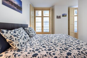 A bedroom with a bed, a window with blinds, and a door.