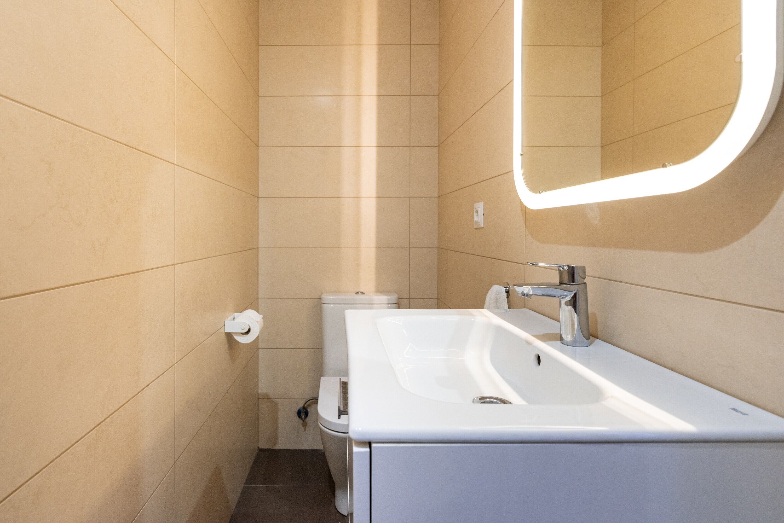 A bathroom with a white sink, a mirror, and a toilet.