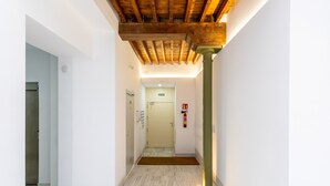 Un couloir avec un plafond en bois, un extincteur et une porte au fond.