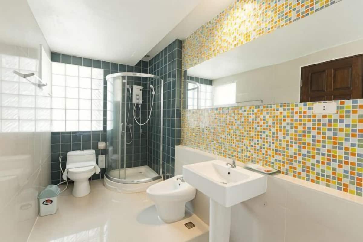 Une salle de bain équipée d’une douche, de toilettes, d’un bidet et d’un lavabo.