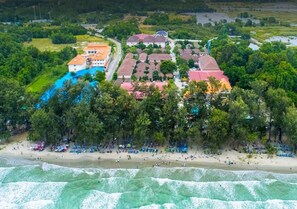 Vista aérea de una propiedad costera con piscina, playa y edificios residenciales.