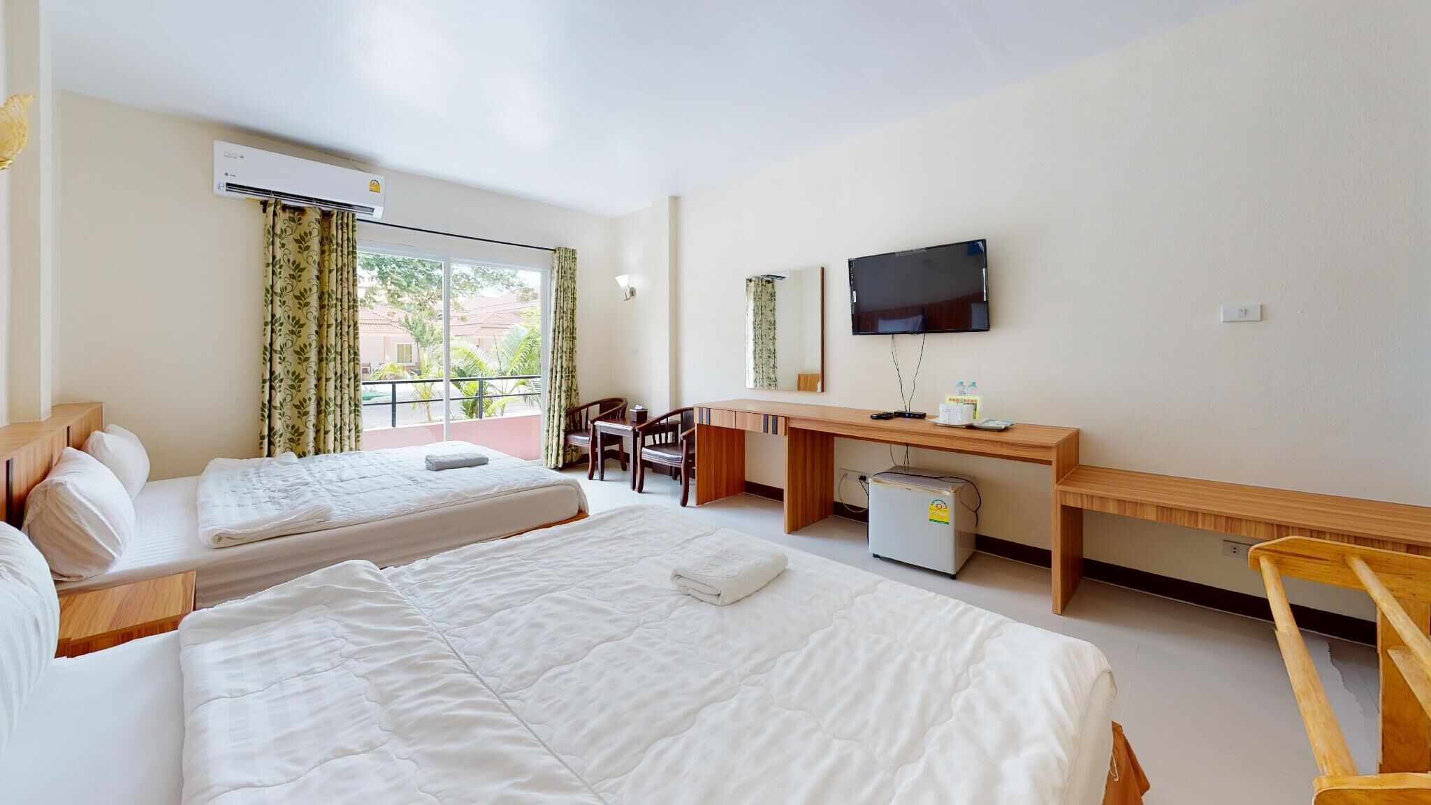 A hotel room with two beds, a desk, a television, and a window with curtains.