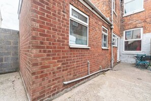 A brick building with two windows, a visible gutter, and a gravel ground. - 3 BedRm Off Newland Ave Shop in Hull Sleeps 5 (Hull)