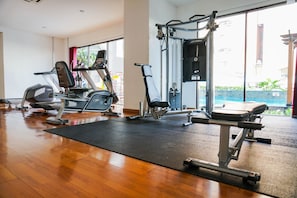 Ein Fitnessraum mit Cardiogeräten, Gewichtstrainern und einem großen Fenster mit Blick ins Freie.