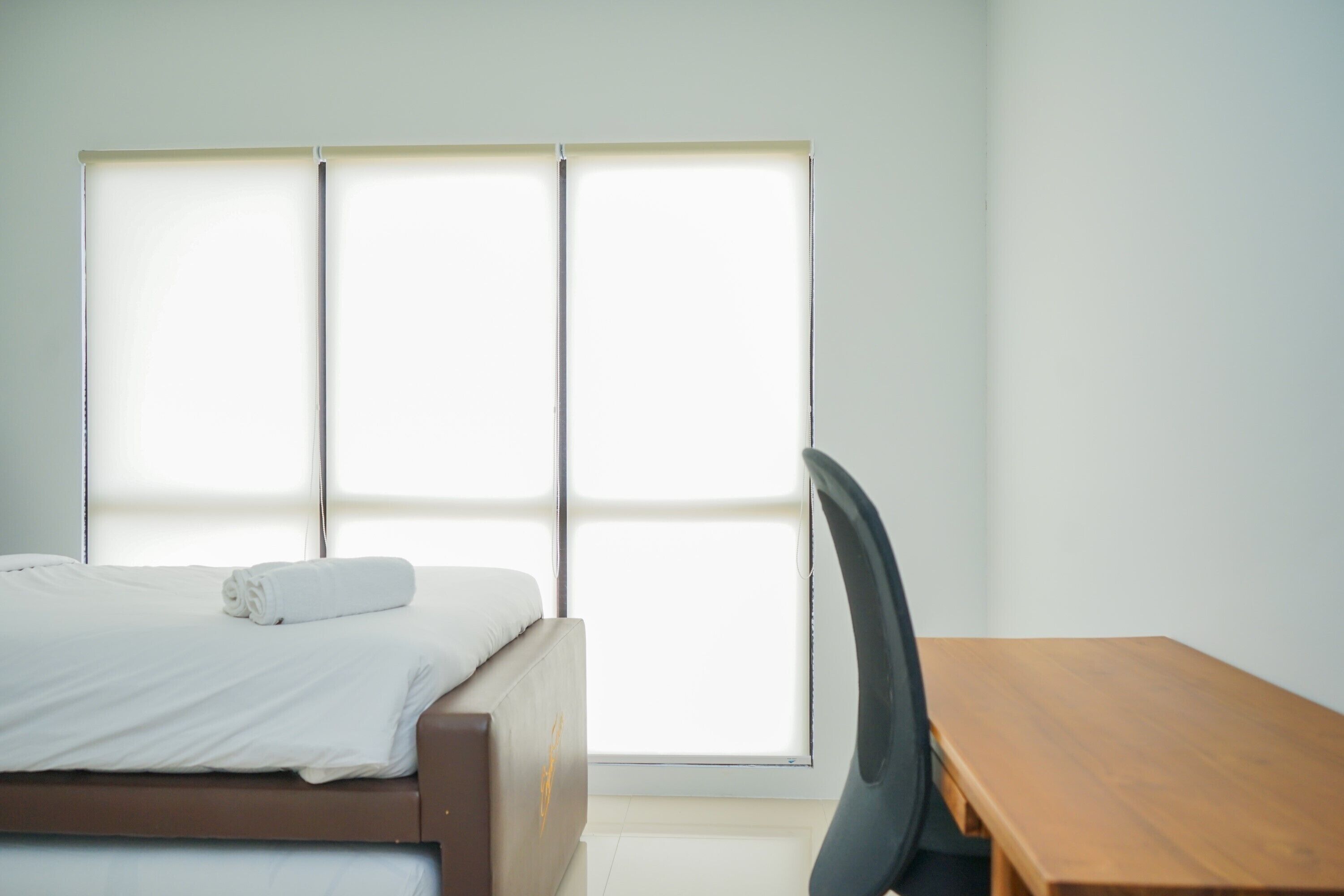 A room with a bed, a wooden table, and a window.