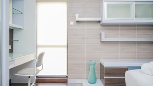 A modern bathroom with a glass shower enclosure, a white vanity with a mirror, and a white chair. - Homey and Modern Tamansari Semanggi 2BR Apartment (Jakarta)